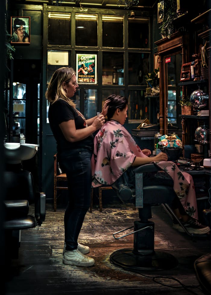 our-experience A hairstylist carefully tends to a client's hair in a warm and cozy salon setting.