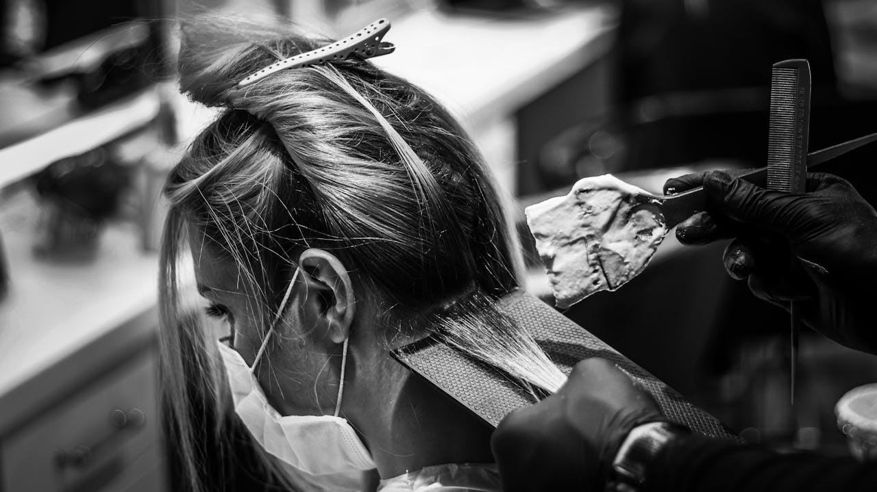 gallery-1 Monochrome image of a woman getting her hair colored in a salon.