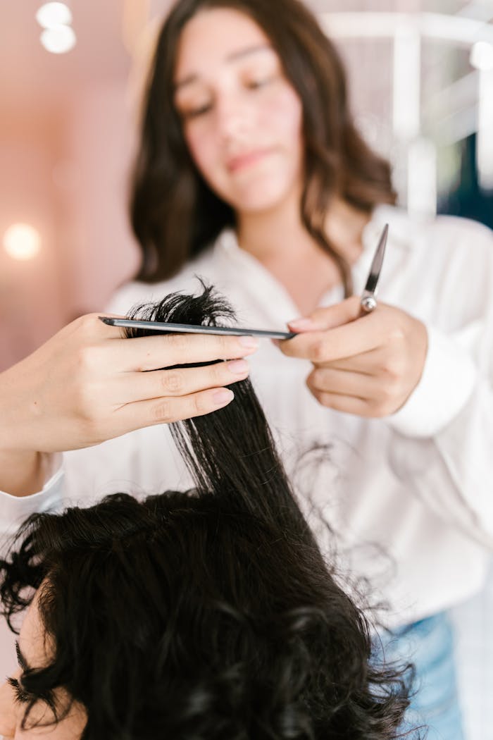 gallery-4 Close-up of hairstylist expertly cutting client’s hair in a salon setting.